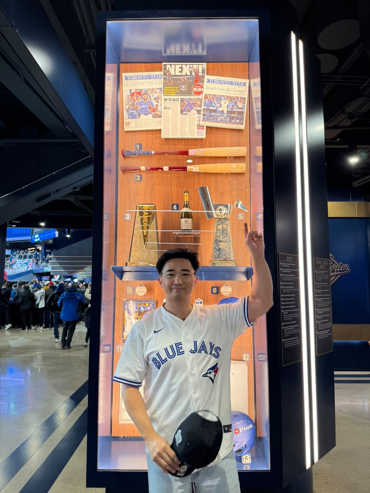 Suyu pointing up at a Blue Jays trophy display case